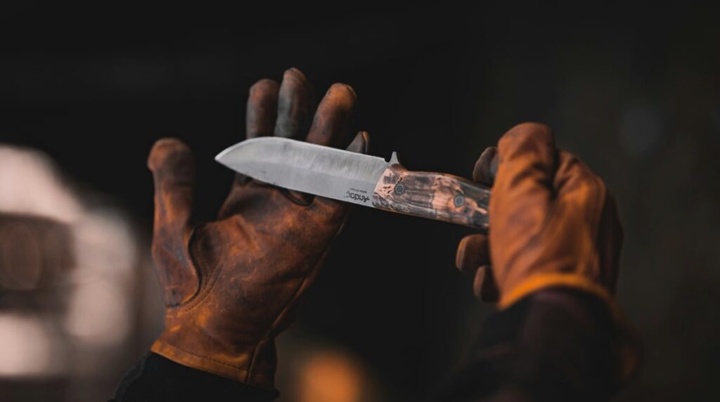 knife with a unique lock hold by man wearing orange gloves