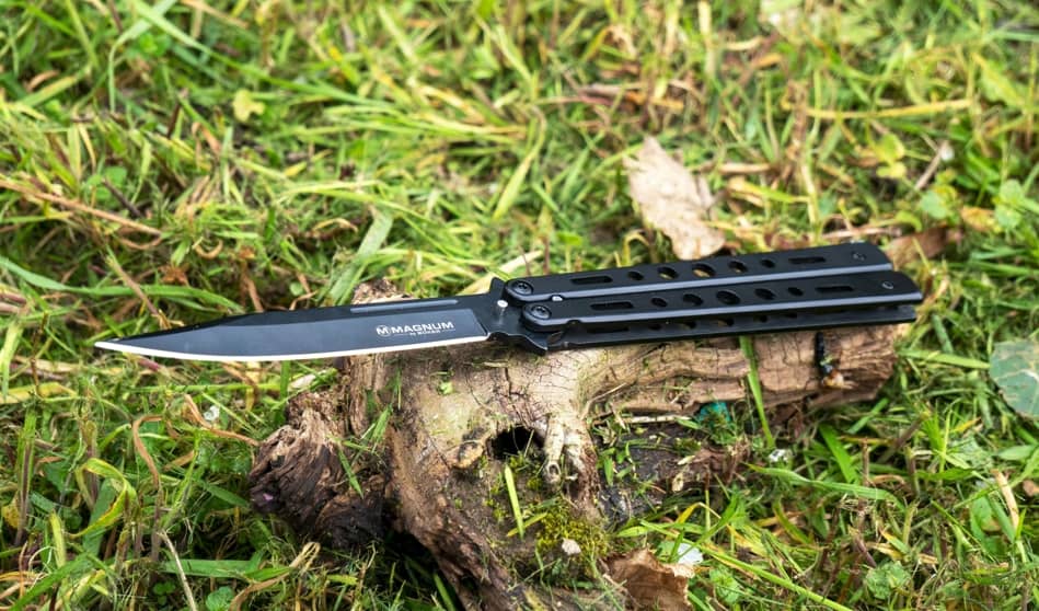 balisong or butterfly knife laying on grass camping outdoor