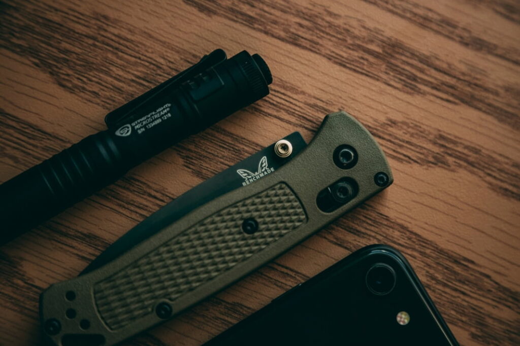 benchmade axis lock knife with phone and pen on the wooden background